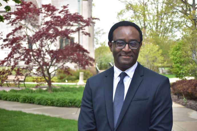 Ben Vinson III stands outside in a suit and blue tie at Case Western Reserve University