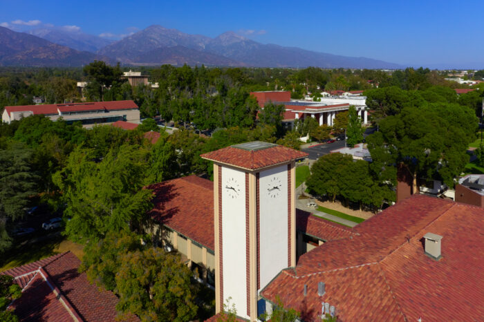Aerial view of the clocktower at Claremont Graduate Union with mountains in the background and blue sky overhead.